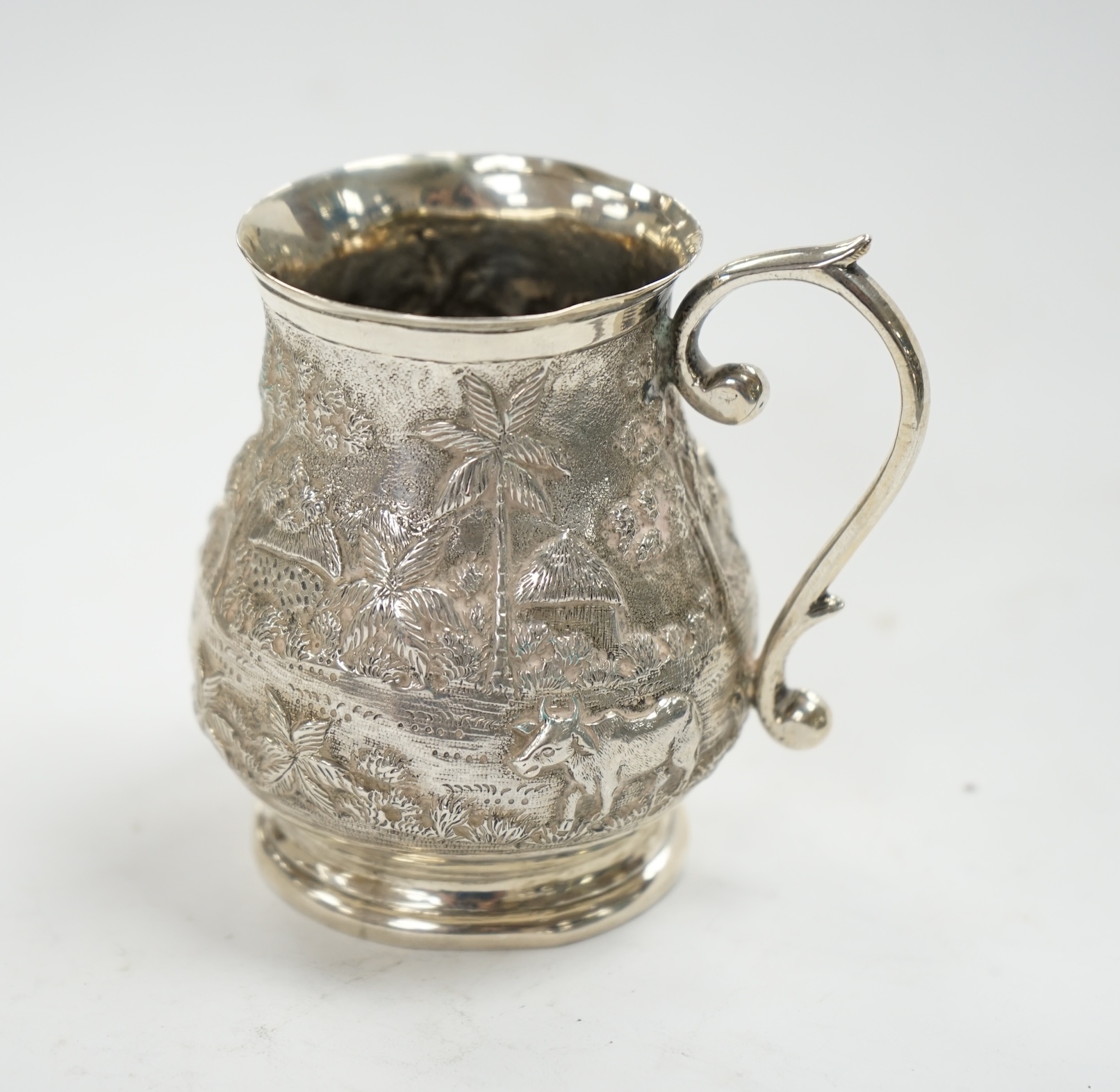 An Indian embossed white metal baluster mug, height 77mm, 94 grams. Condition - poor to fair